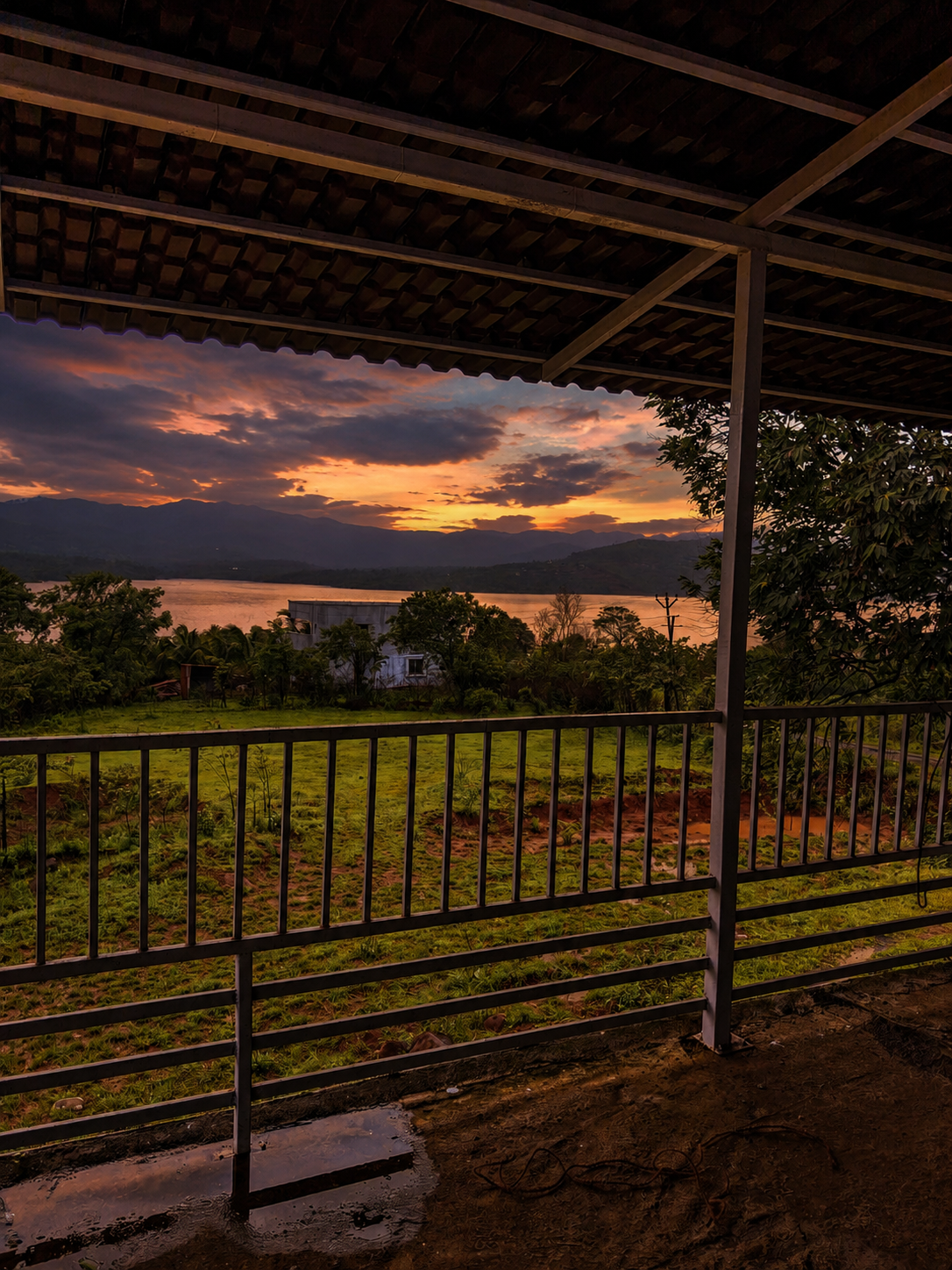Balcony view of the lake and hills under a dramatic sunset sky